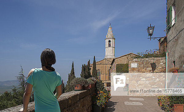 Frau an Steinmauer und Kirche in der Toskana  Italien