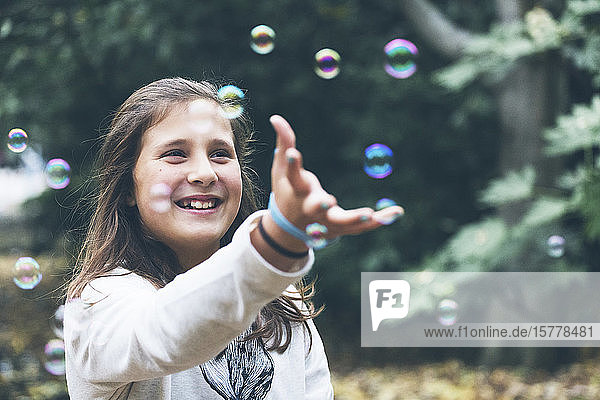 Lächelndes Mädchen spielt mit Seifenblasen