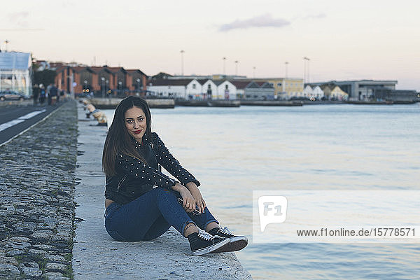 Frau sitzt auf einem Fußweg am Meer in Lissabon  Portugal