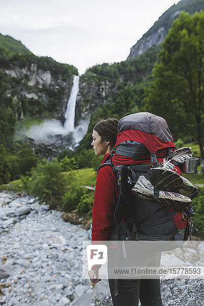 Frau mit Rucksack und Wasserfall in der Ferne