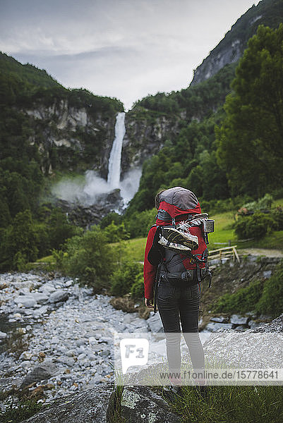 Woman wearing backpack with waterfall in distance