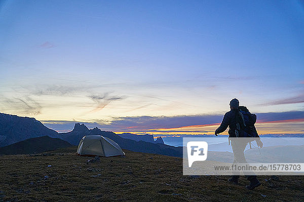 Hiker walking to his tent at sunset  Canazei  Trentino-Alto Adige  Italy