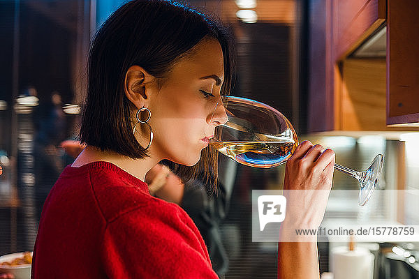 Woman drinking wine at party in apartment