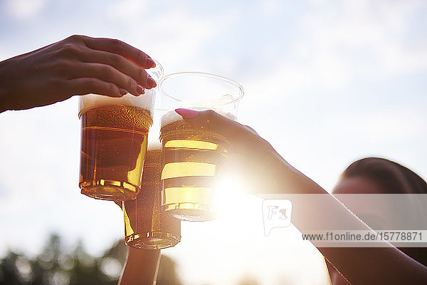 Drei junge Freundinnen stoßen beim Holi-Fest mit Biergläsern an