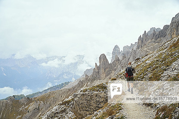 Wanderer auf Feldweg am Berghang Canazei Trentino-Südtirol Italien