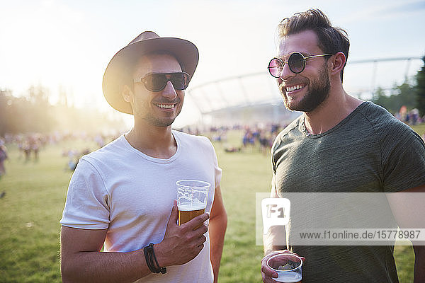 Zwei junge männliche Freunde mit Biergläsern beim Holi-Fest