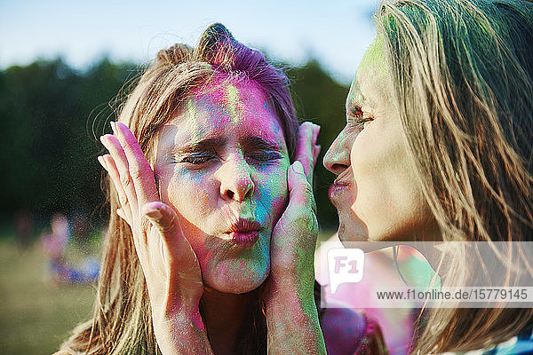 Zwei junge Frauen mit mit farbigem Kreidepulver bedeckten Gesichtern beim Holi-Fest