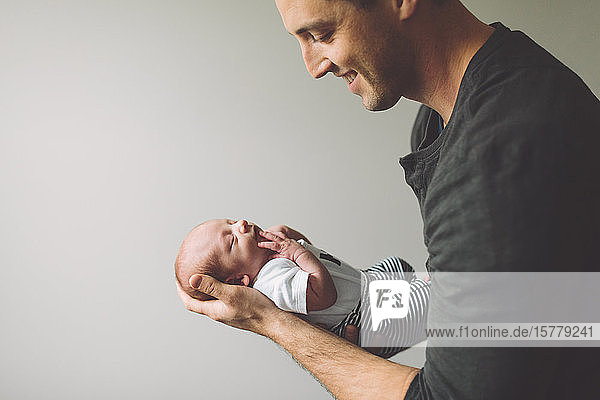 Father holding newborn baby boy smiling
