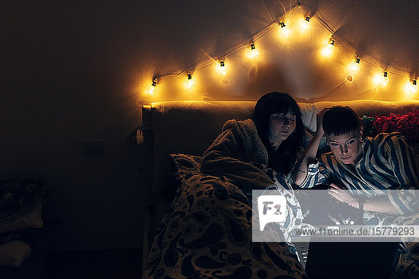 Frauen im Bett im Dunkeln mit Laptop