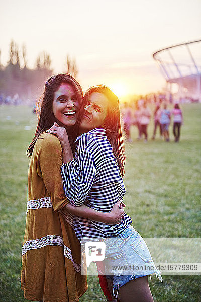 Zwei mit farbigem Kreidepulver bedeckte junge Frauen umarmen sich beim Holi-Fest  Porträt
