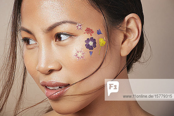 Frau mit floraler Gesichtsbemalung auf der Wange