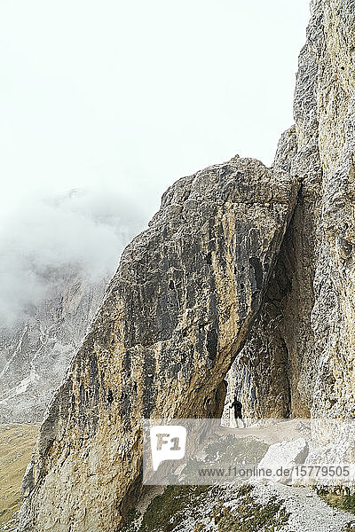 Hiker passing under stone arch  Canazei  Trentino-Alto Adige  Italy