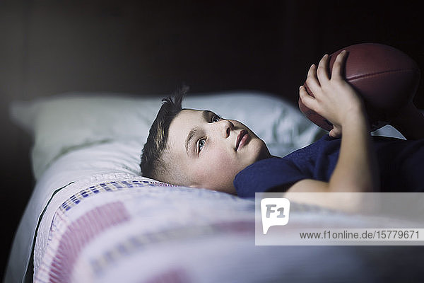 Junge im Bett mit American Football