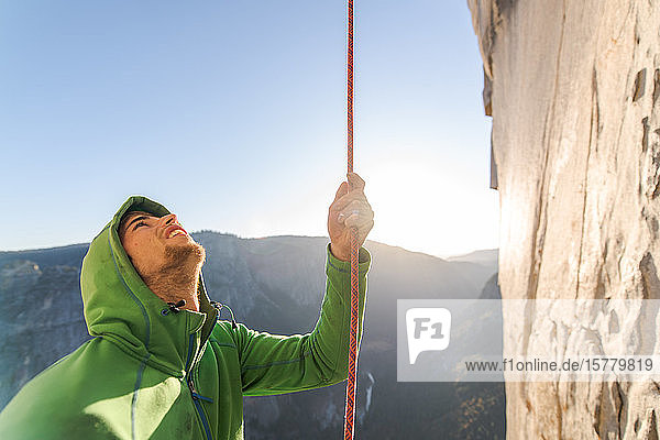 Bergsteiger der sich während des Aufstiegs an der Steilwand von The Nose El Capitan Yosemite National Park am Seil festhält.