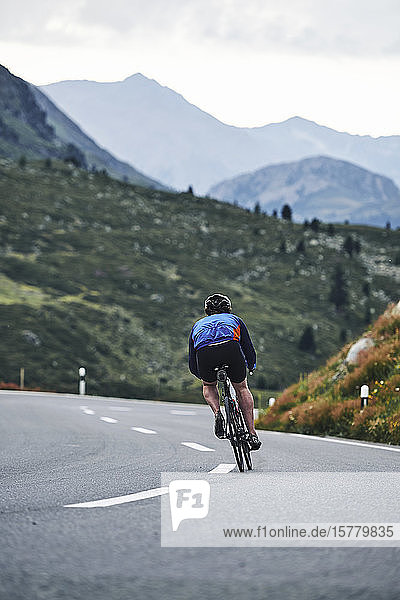 Male cyclist cycling on mountain road  Fluela Pass  Davos  Graubunden  Switzerland