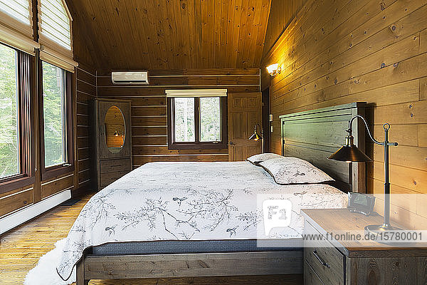 Interior view of master bedroom with king size bed inside a log home Quebec Canada.