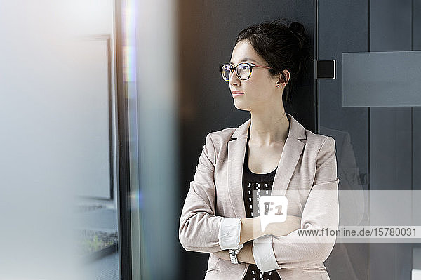 Porträt einer jungen Geschäftsfrau mit dunkelbraunem Haar und Brille.