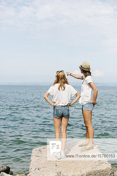 Two female friends standing at the lakeside  Lake Garda  Italy