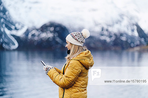 Tourist mit Smartphone auf Hamnoy Lofoten Norwegen