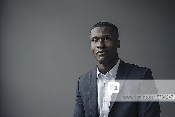 Portrait of young businessman against grey background