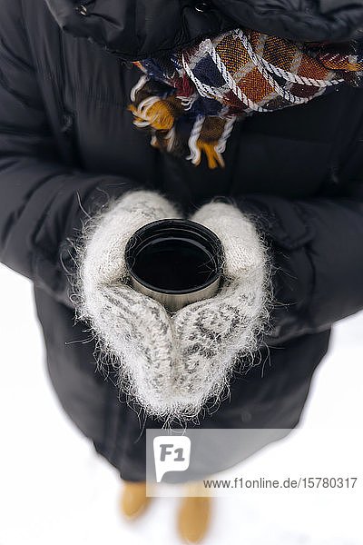 Woman's hands holding thermo mug outdoors