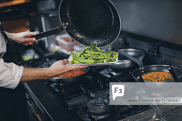 Chefkoch bereitet grünes Spargelgericht in der Restaurantküche