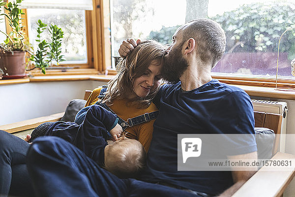 Woman on the sofa breastfeeding her little son and sharing time with her husband