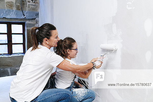 Mother and daughter painting a wall of her new house together