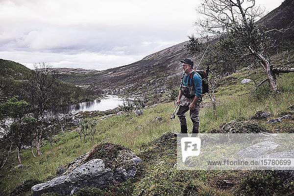Fly fisherman standing at river bank with mountains  Lakselv  Norway