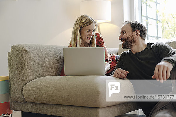 Couple sitting at home on couch  using laptop