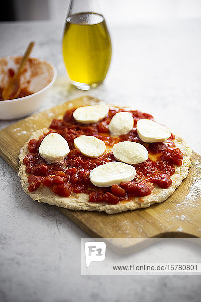 Halbfertige Pizza Margharita auf Schneidebrett