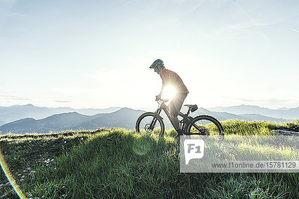 Mountainbiker gegen die Sonne auf einem Weg in Graubünden  Schweiz