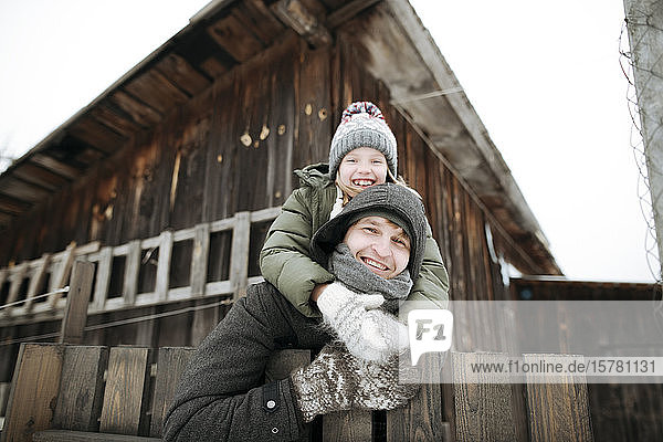 Porträt eines glücklichen Vaters  der seine Tochter im Winter huckepack nach draussen trägt
