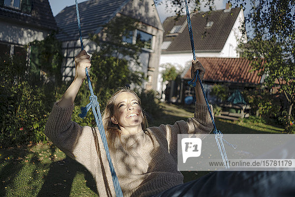 Blond woman swinging in her garden