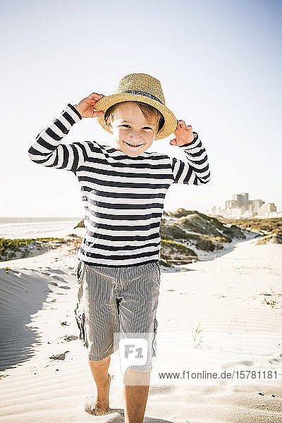 Portrait of smiling boy with hat on the beach