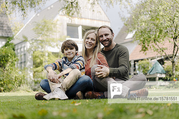 Happy family sitting on grass in their garden