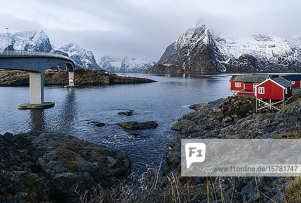 Brücke und rote Hütten an der Küste  Hamnoy  Lofoten  Norwegen