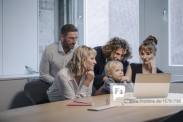 Business team with boy looking at laptop in office