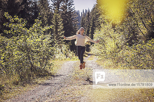 Mädchen rennt und springt auf einem Waldweg und hat Spaß