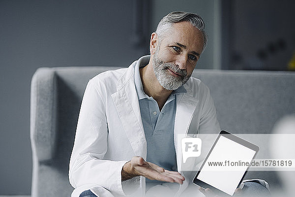 Porträt eines lächelnden Arztes mit digitalem Tablett bei der Konsultation