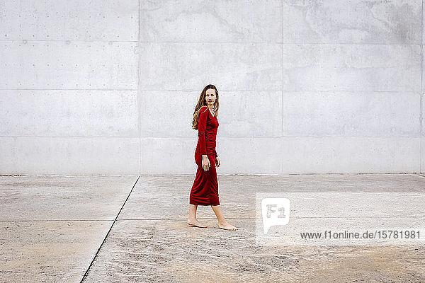 Porträt einer barfüssigen jungen Frau in rotem Kleid im Freien