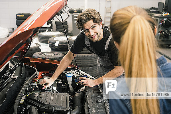 Automechaniker betrachtet Kunden in der Werkstatt