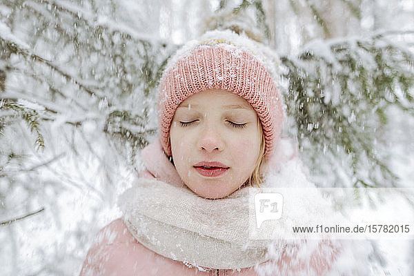 Portrait of girl with eyes closed in winter forest