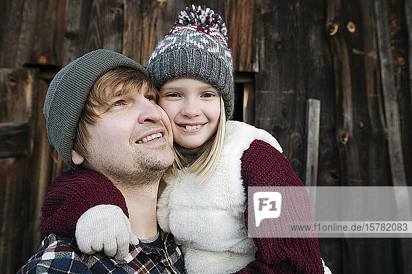 Glückliche Tochter umarmt Vater im Winter draussen