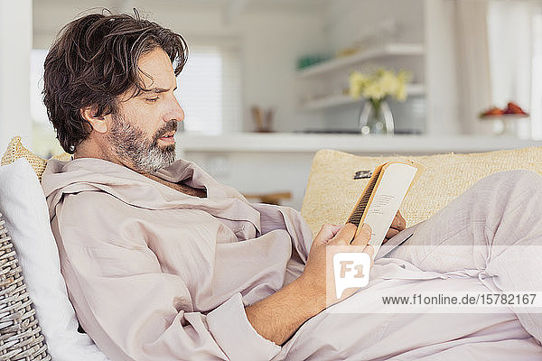 Relaxed man in bathrobe reading a book