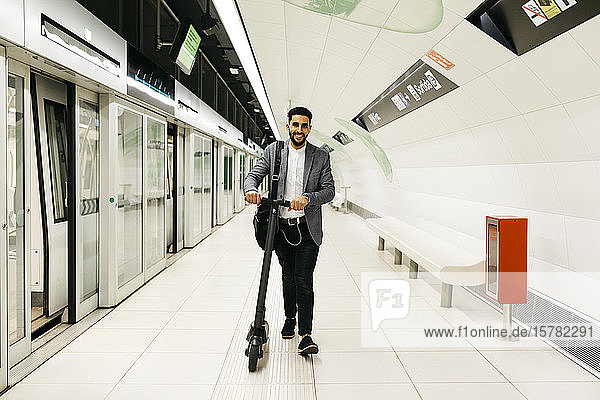 Young businessman with electric scooter in subway station