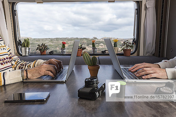 Scherenschnittansicht eines Paares  das im Wohnmobil an Laptops arbeitet  Es Mercadal  Menorca  Spanien