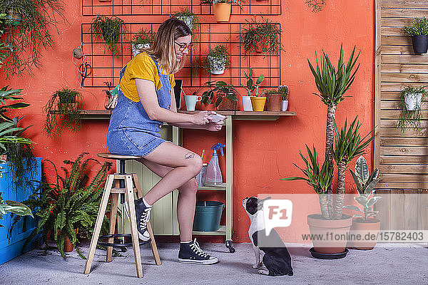 Frau macht Handyfoto von ihrem Hund auf der Terrasse