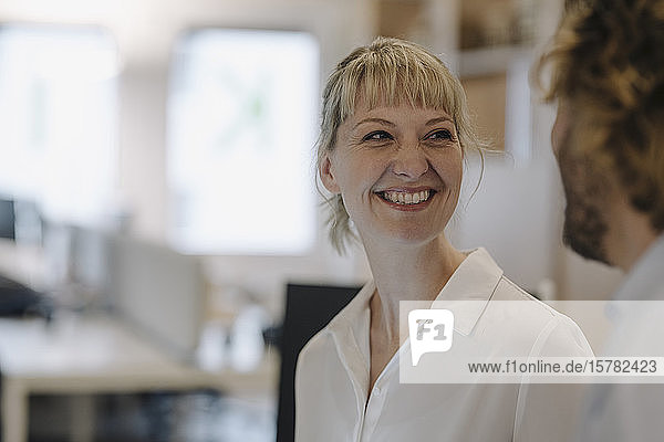 Portrait of smiling businesswoman looking at businessman in offce