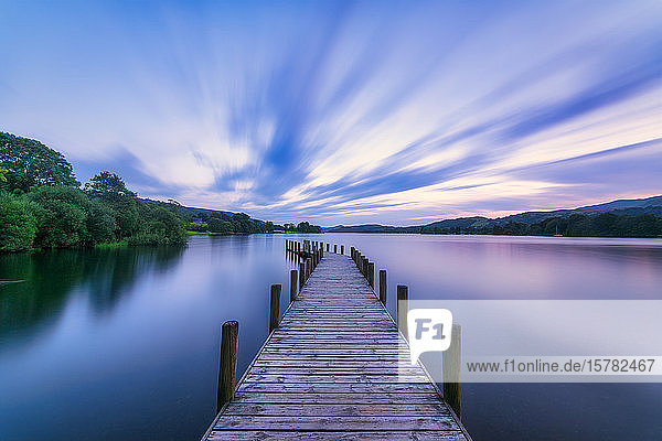 Grossbritannien  England  Langzeitbelichtung von Wolken über dem Steg des Coniston Water Sees in der Abenddämmerung